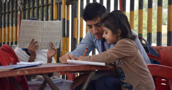 teenage student volunteering, teaching younger kids to read